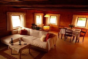 Ein gemütliches Zimmer mit einer Couch, einem Esstisch, Stühlen und einer Lampe.