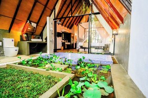 Un jardín interior con bancales elevados, una zona de cocina y un comedor con vistas al exterior.