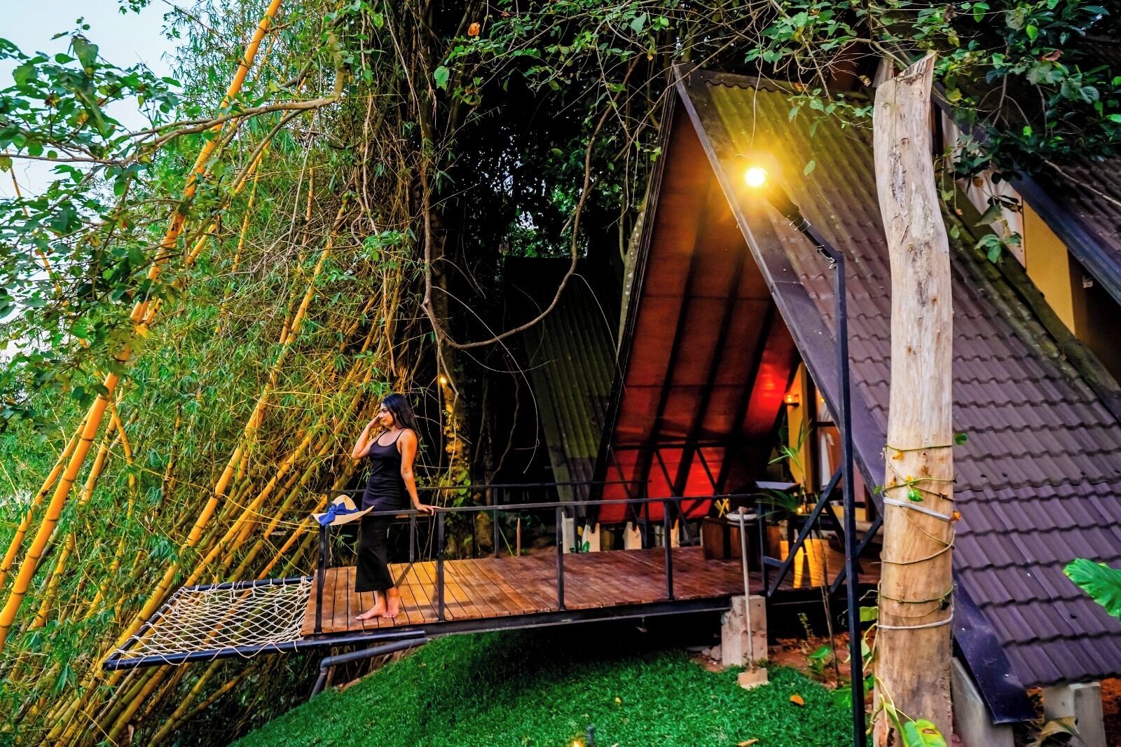 A treehouse with a wooden platform, netted climbing area, and a red-roofed structure.