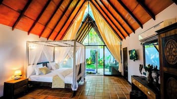 A bedroom with a four-poster bed, a nightstand, a dresser, and a view of the outdoors.