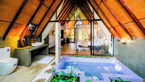 Una habitación acogedora y bien iluminada con un ventanal, una cama, una mesita y una bañera.