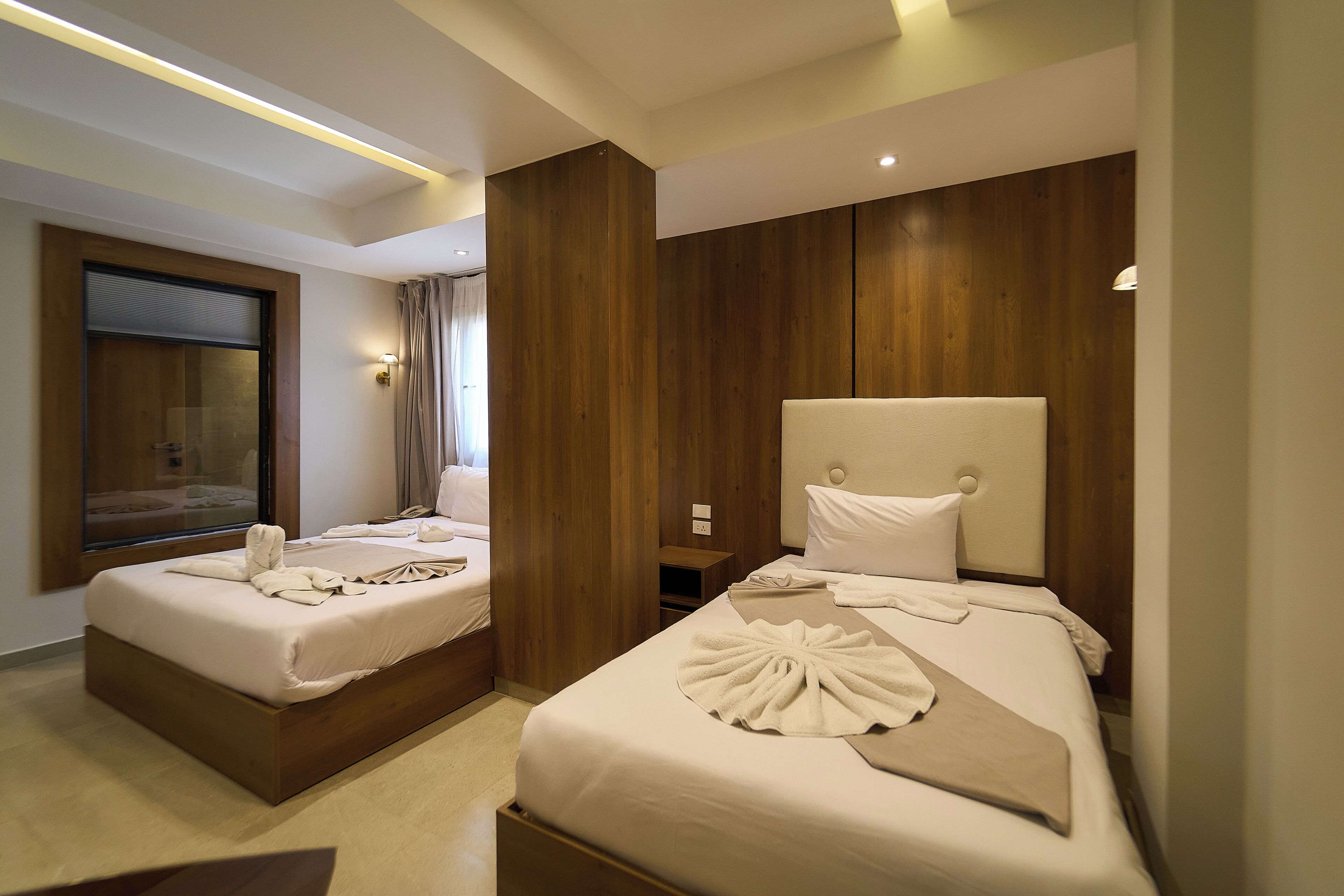 Habitación de hotel con dos camas, un espejo grande y paneles de madera en las paredes.