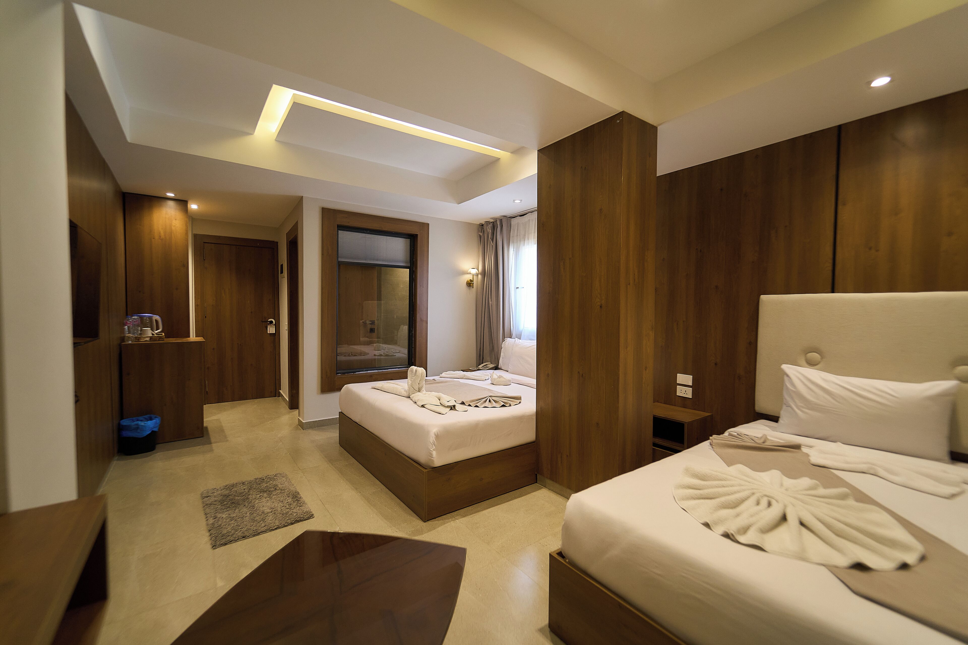 A hotel room with a large bed, a bedside table, a desk, a mirror, and a wardrobe.
