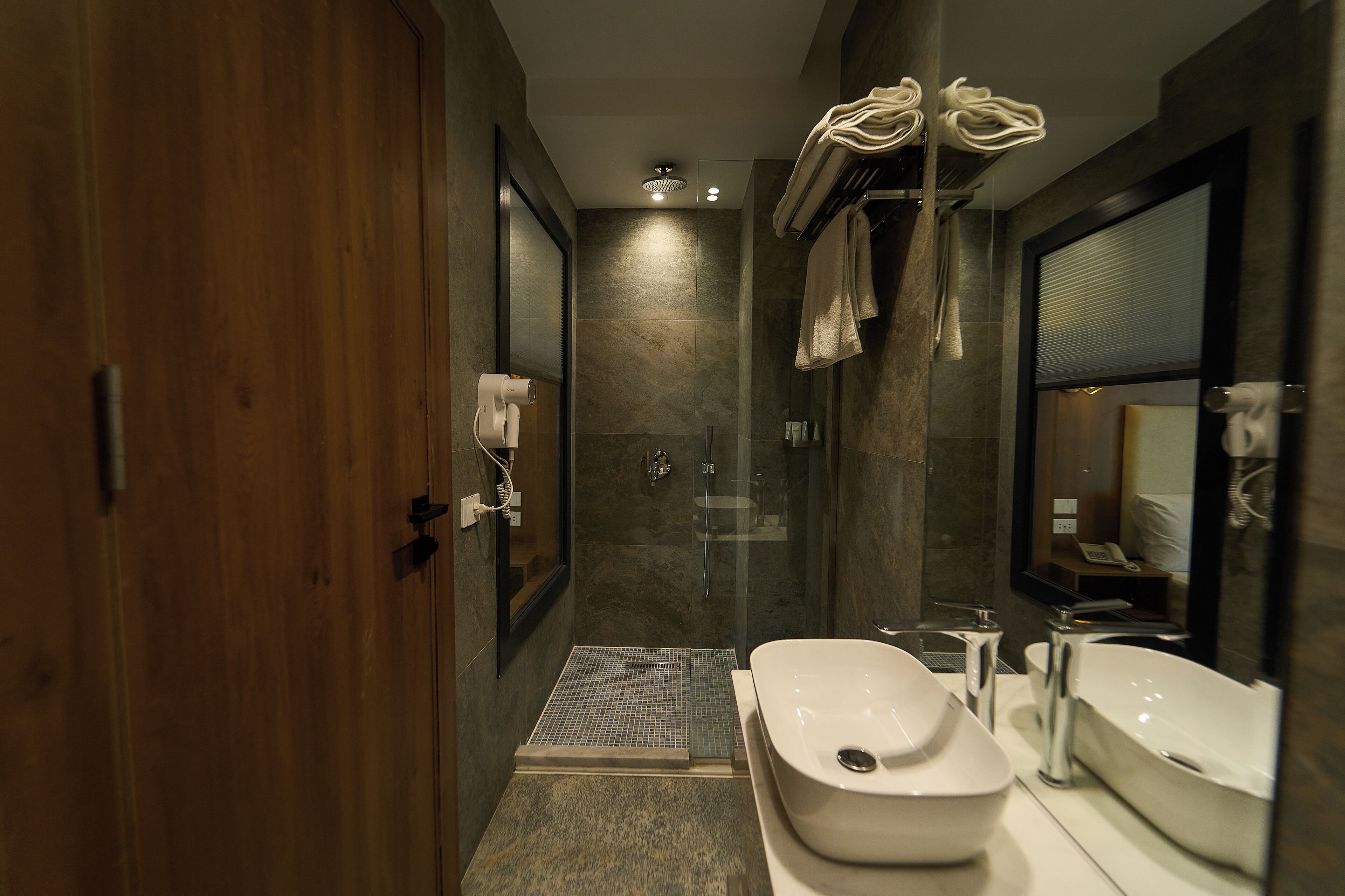 Une salle de bain moderne avec une porte en bois, une douche, un bidet et un grand miroir.