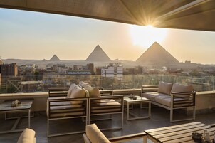 Une terrasse sur le toit, aménagée avec des sièges et offrant une vue sur les pyramides.