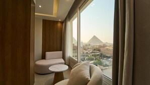 A modern room with a view of a pyramid, a round table, and a sofa. - Kemet Pyramids View Hotel (Giza)