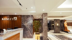 A hotel reception area with a marble reception desk, a wooden reception desk, and a statue. - Kemet Pyramids View Hotel (Giza)