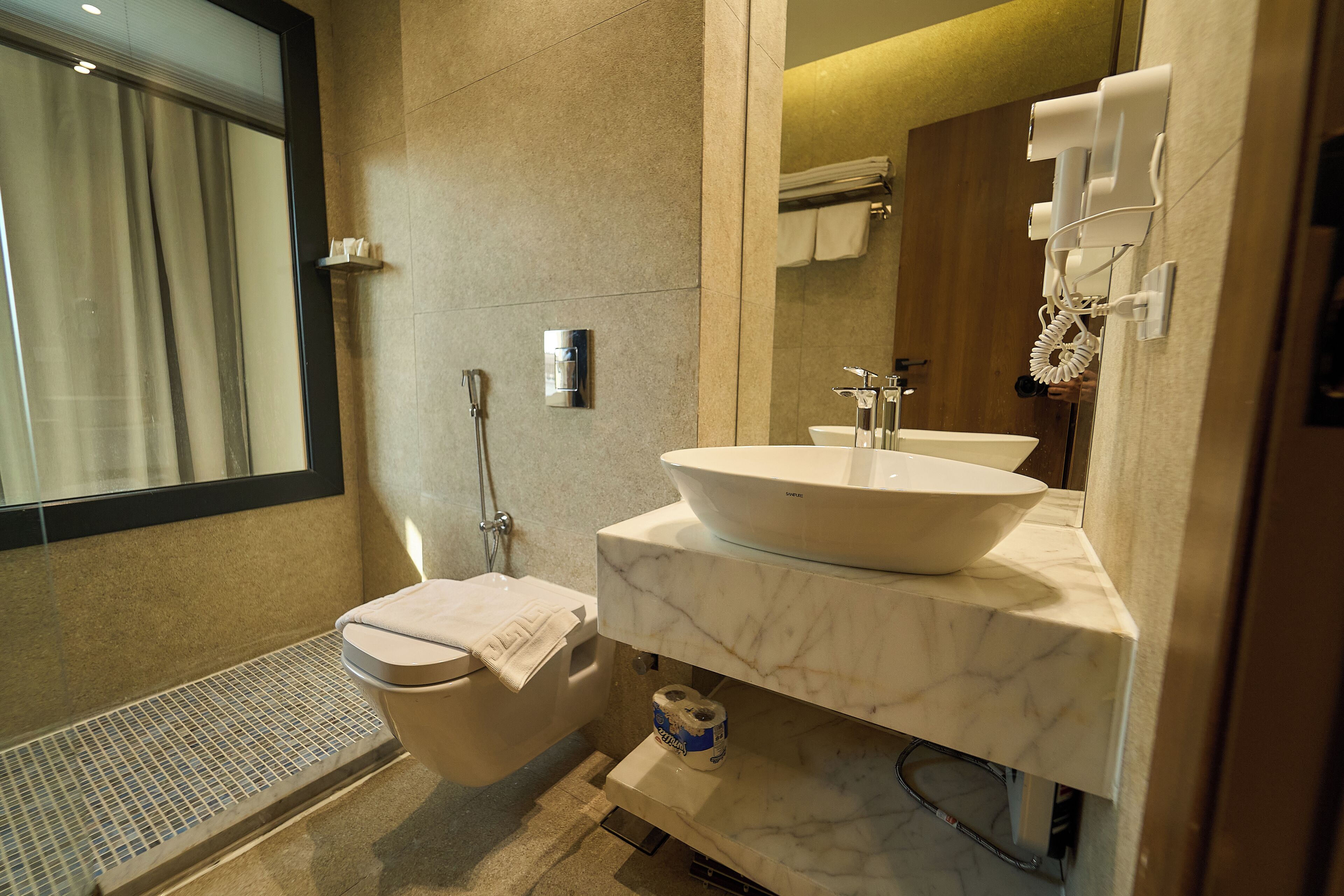 A modern bathroom with a toilet, bidet, sink, and mirror.