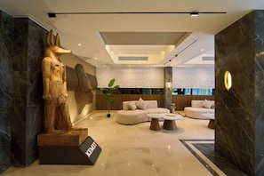 A modern interior with a marble floor, a statue, a sofa set, and a decorative wall panel. - Kemet Pyramids View Hotel (Giza)