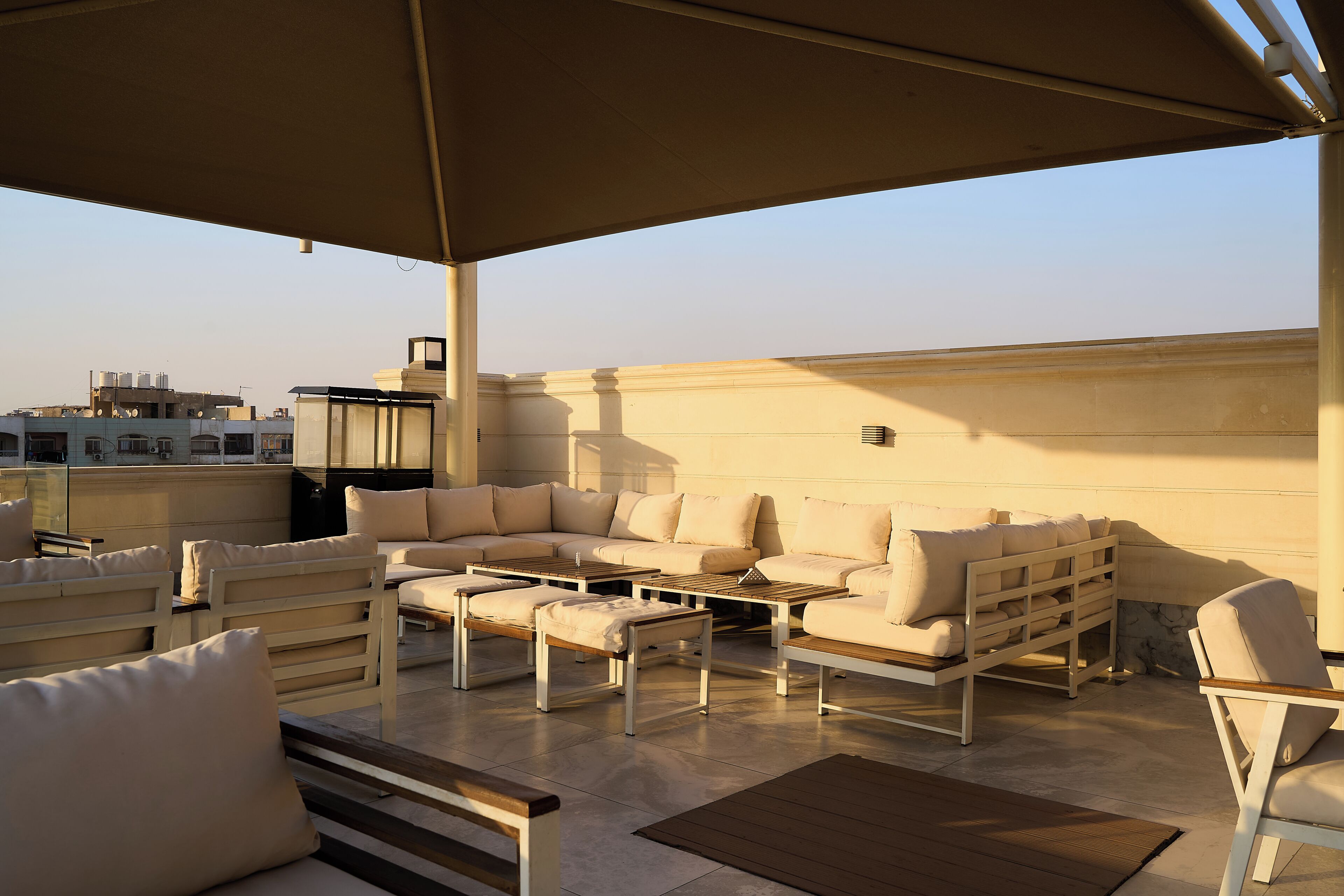 Terraza en la azotea con mobiliario exterior, incluyendo sofás y una mesa, bajo un toldo grande.