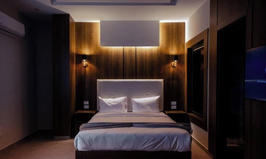 Un dormitorio moderno con una cama grande, paneles de madera en las paredes e iluminación empotrada.
