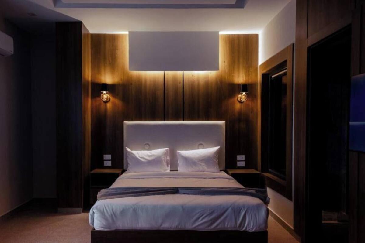 Un dormitorio moderno con una cama grande, paneles de madera en las paredes e iluminación empotrada.