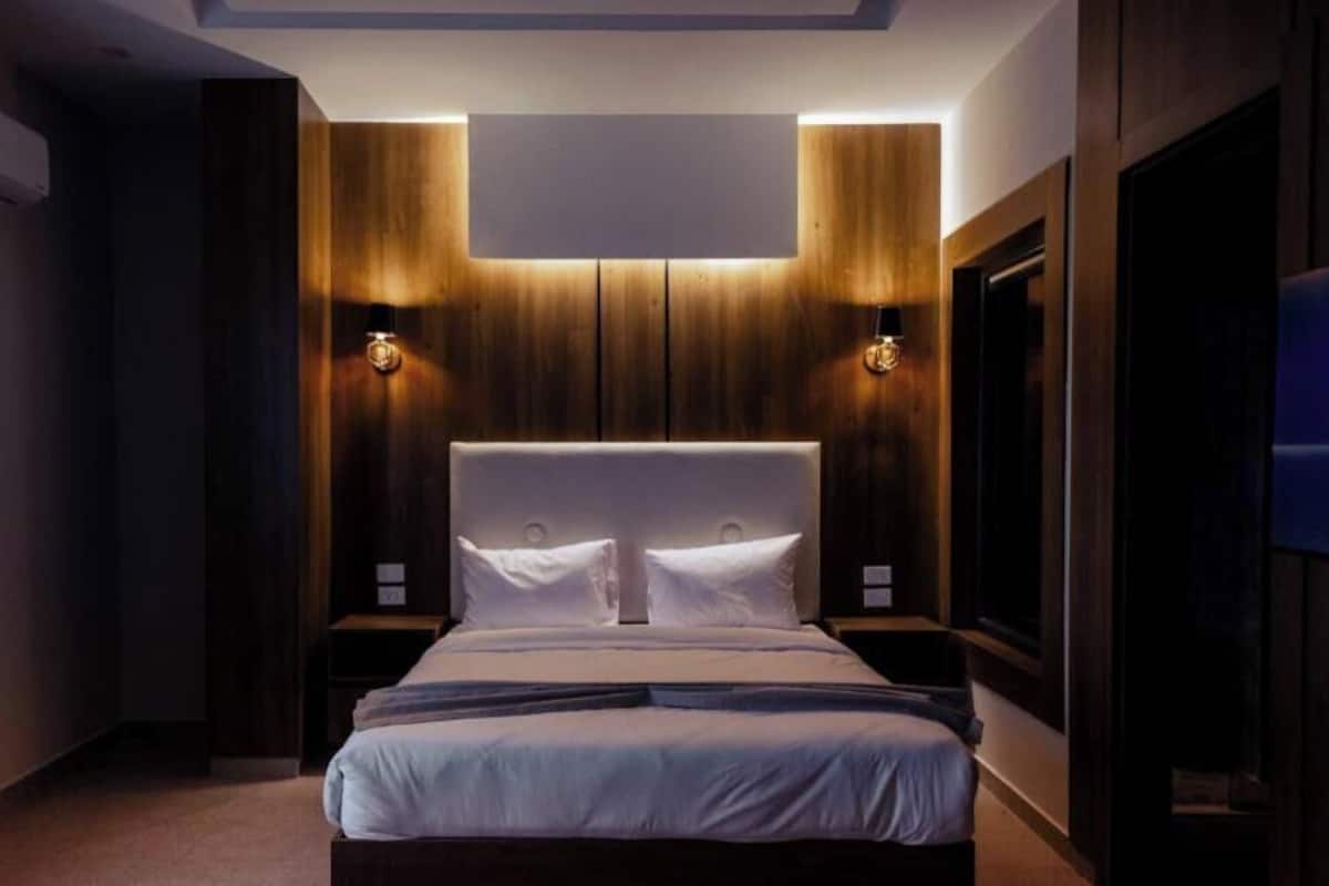 Un dormitorio moderno con una cama grande, paneles de madera en las paredes e iluminación empotrada.