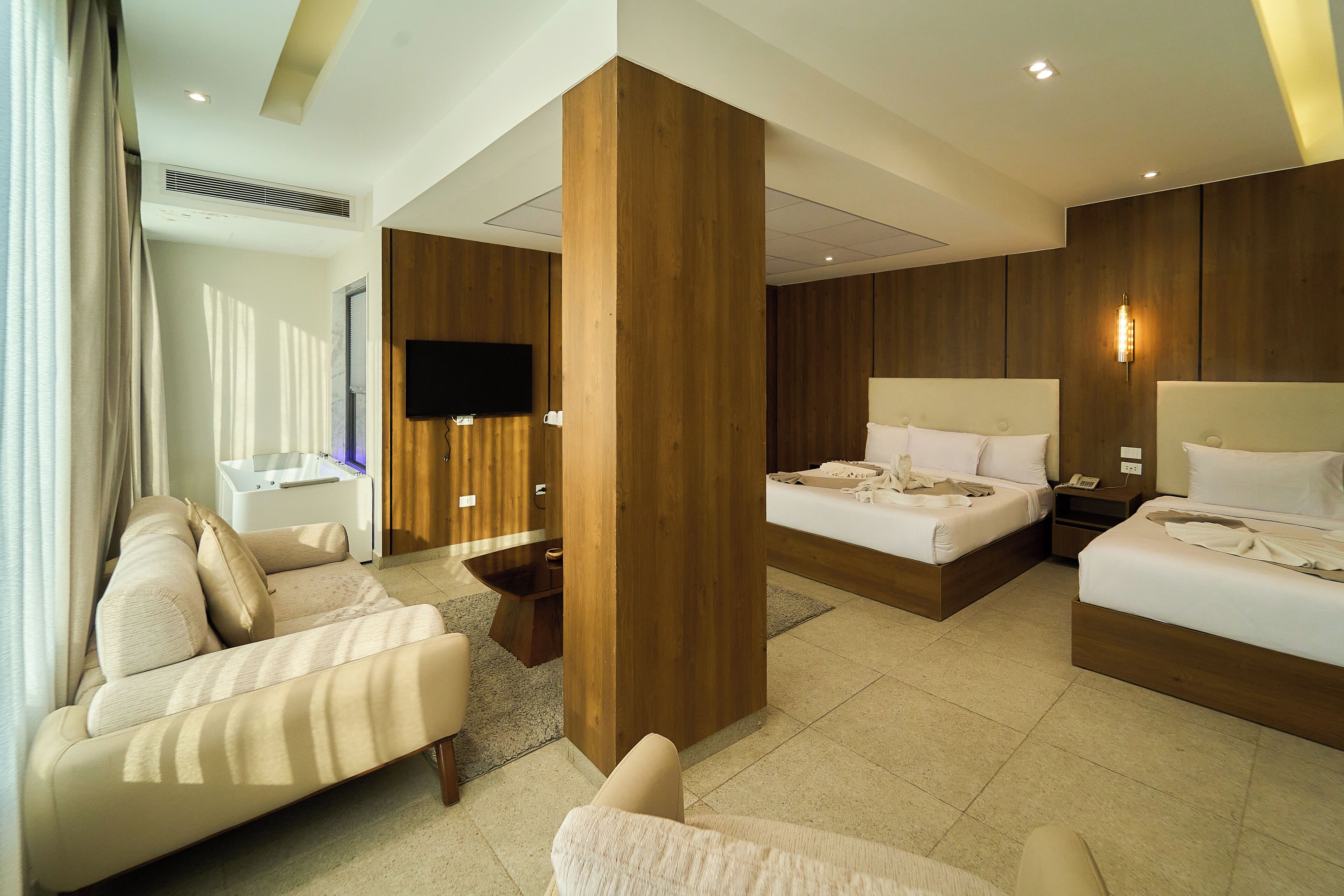 A modern hotel room with a large bed, a sofa, a desk, and a television.
