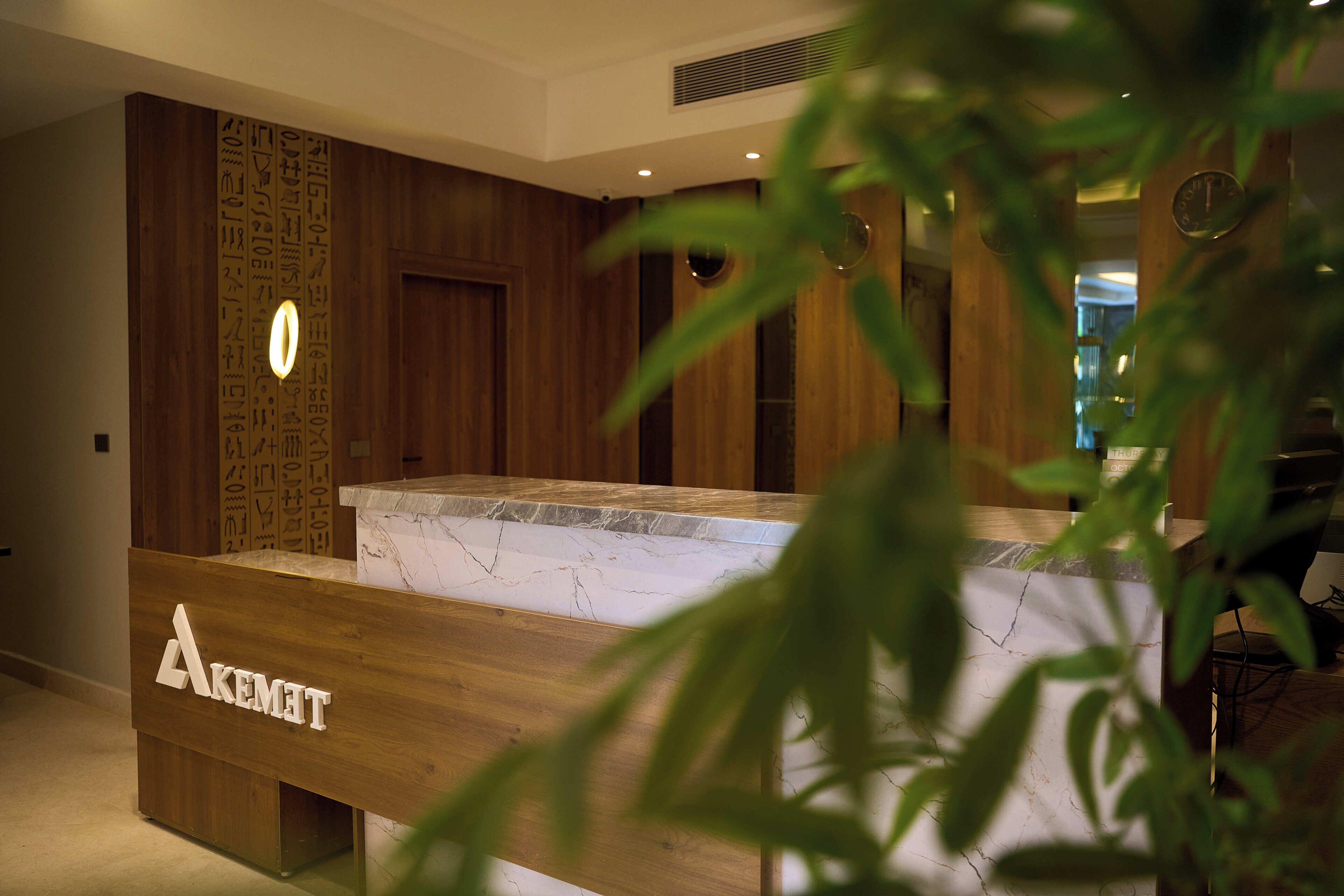 A reception desk with a wooden finish and a marble top. There is a sign with the name 'AKEMIT' on the desk.