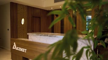 A reception desk with a wooden finish and a marble top. There is a sign with the name 'AKEMIT' on the desk.