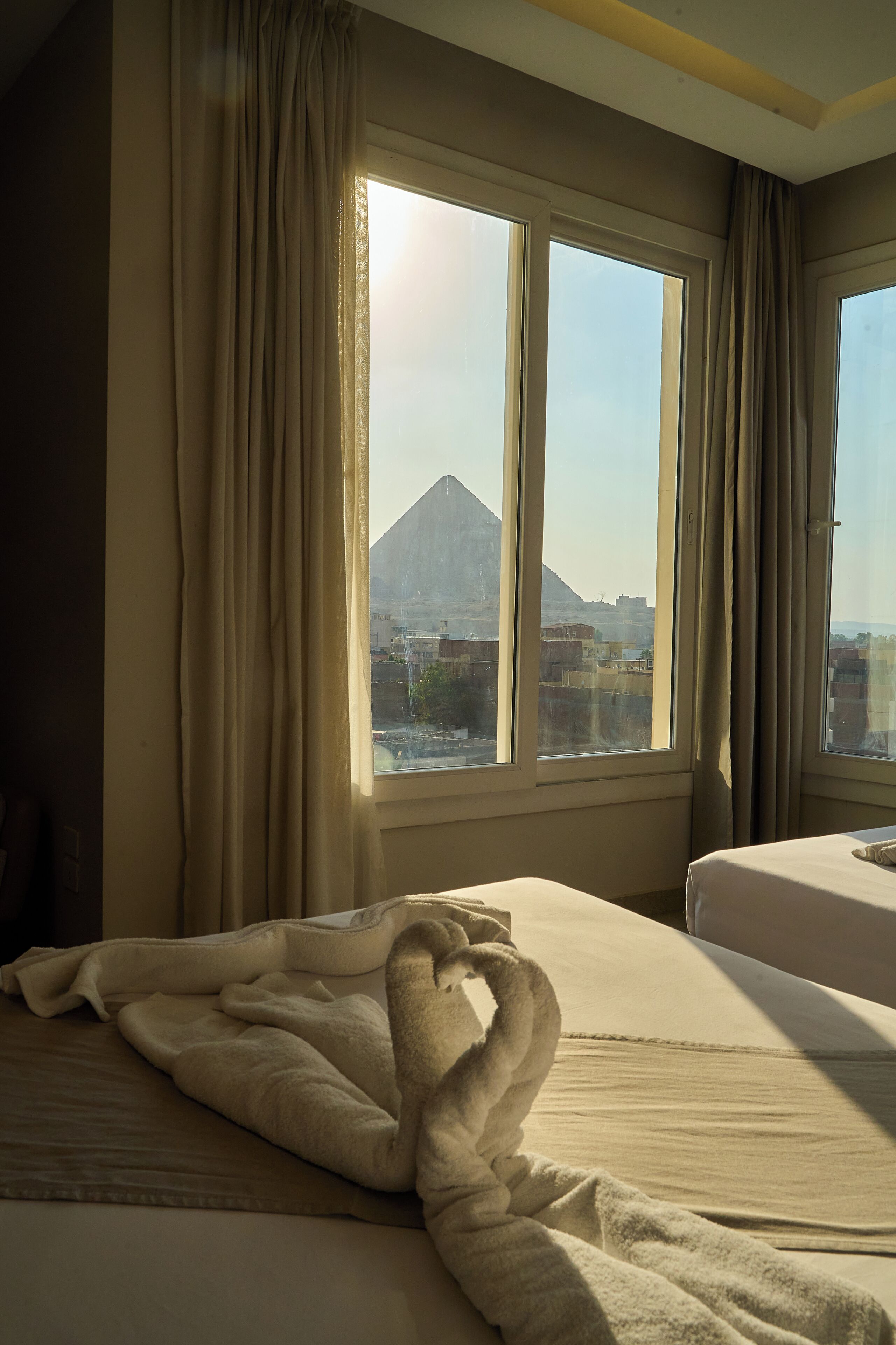 Ein Hotelzimmer mit zwei Betten, Blick auf einen Berg und Vorhängen an den Fenstern.
