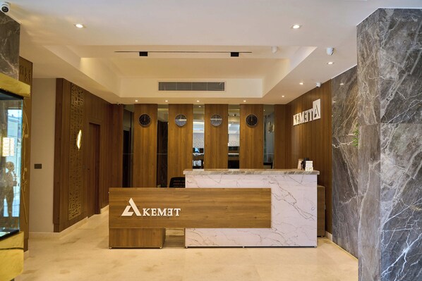 A hotel reception area with a wooden reception desk, marble walls, and clocks on the wall. - Kemet Pyramids View Hotel (Giza)
