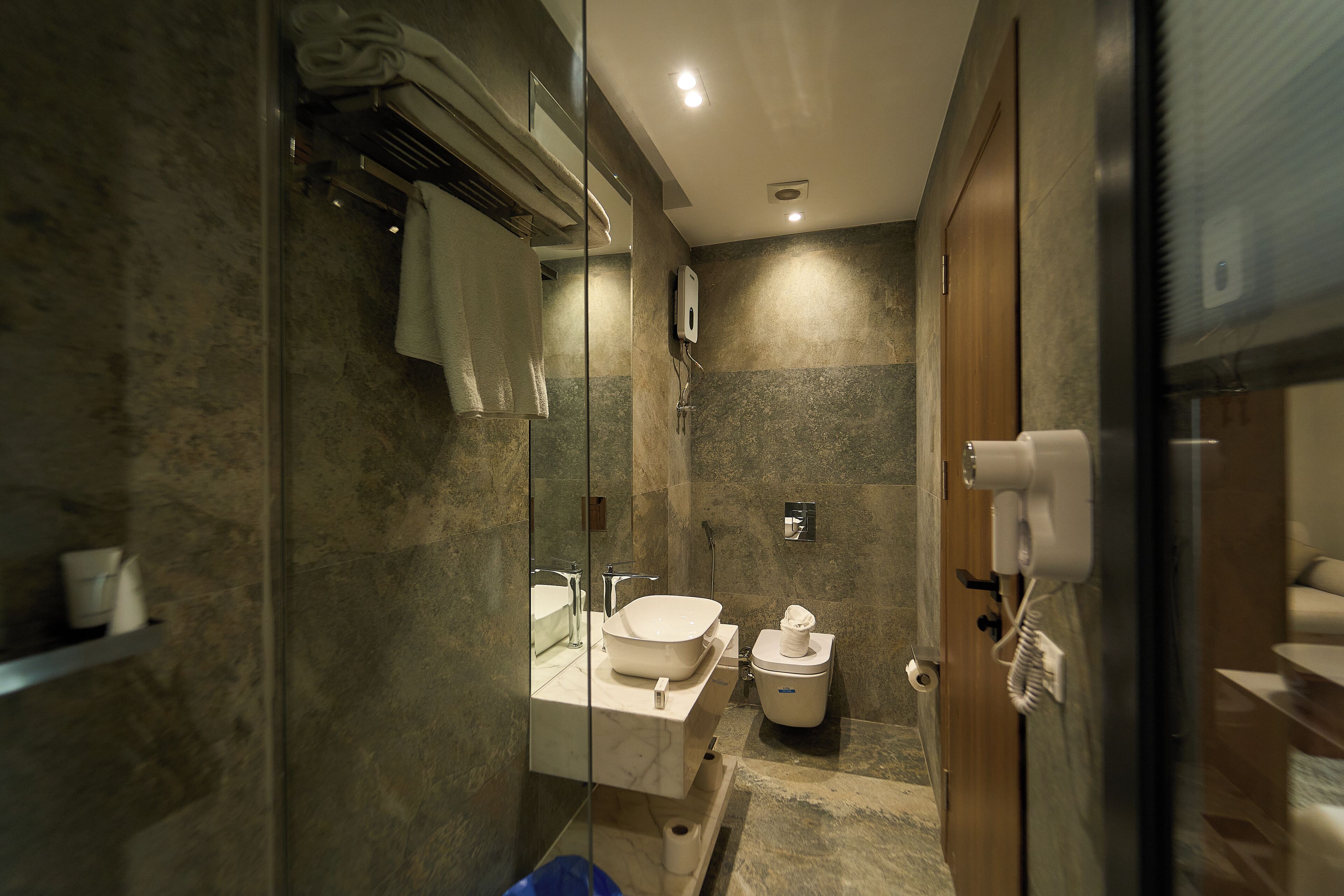 A modern bathroom with a glass partition, a sink, a toilet, and a shower area.