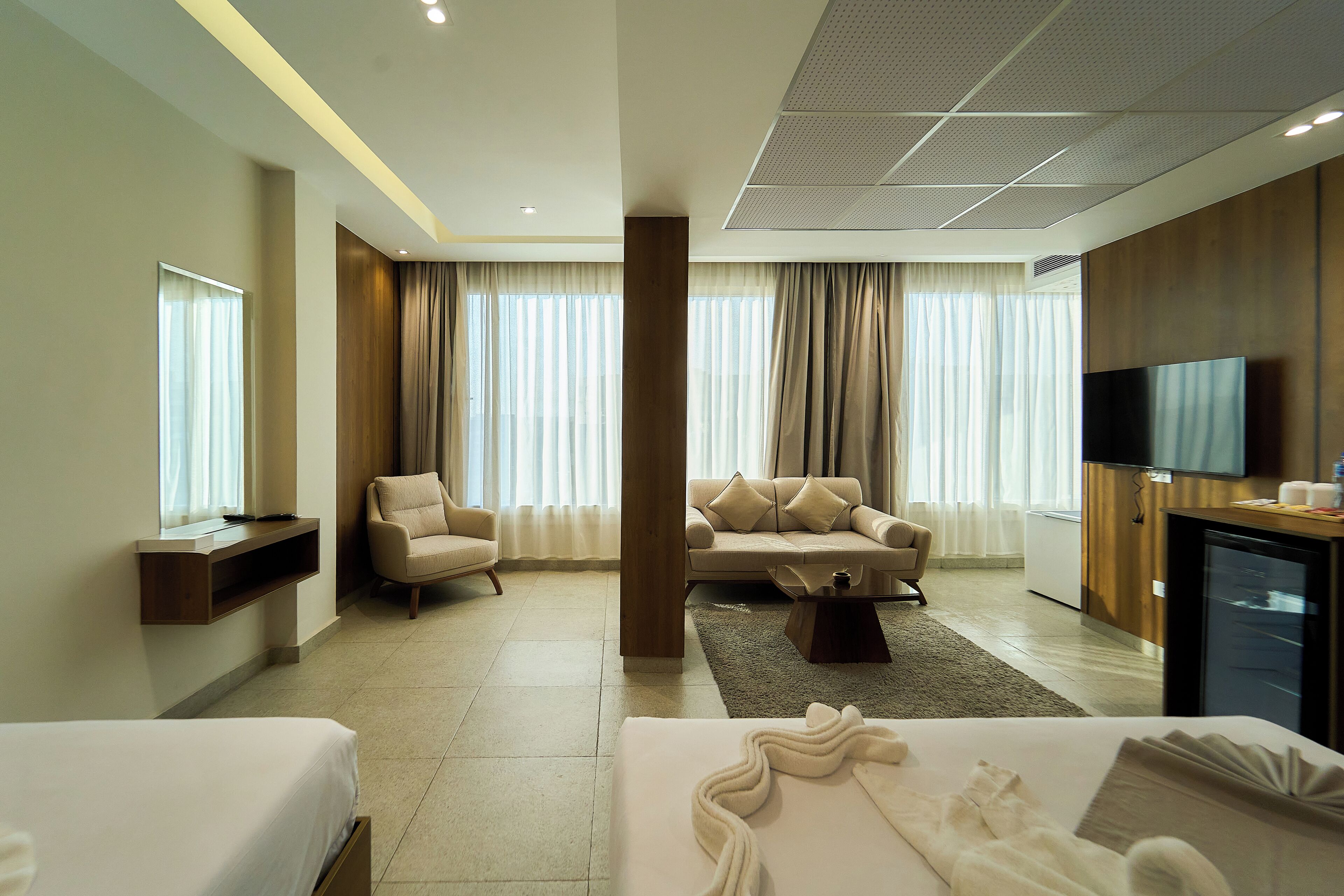 A hotel room with a bed, a sofa, a TV, and a desk.