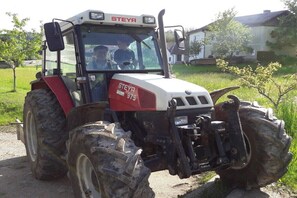 Un grand tracteur de la marque STEYR, modèle 975, est garé sur un chemin de terre.
