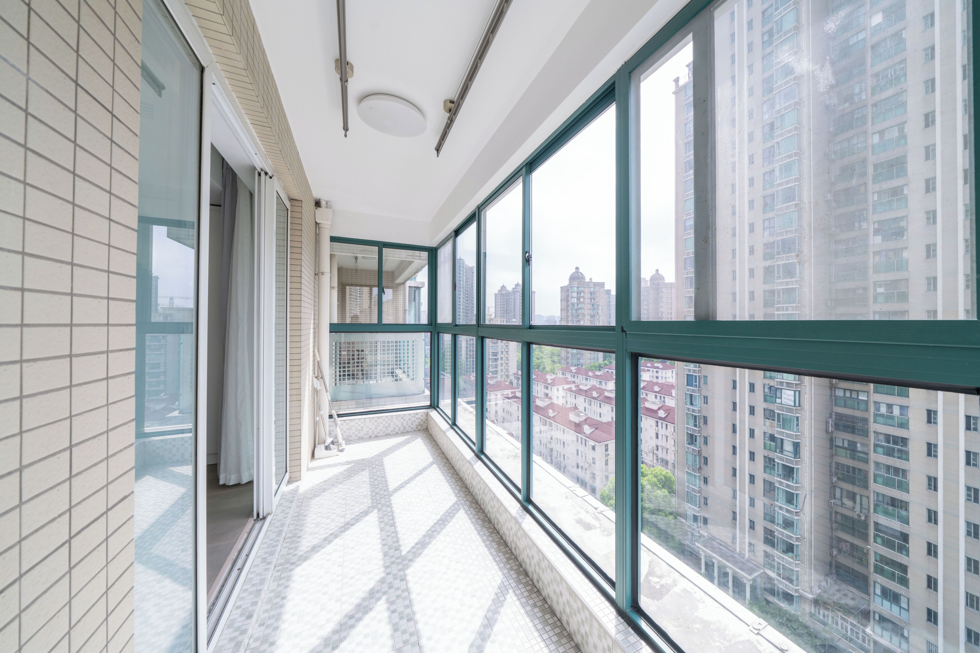 A corridor with large windows, a tiled floor, and a view of high-rise buildings.