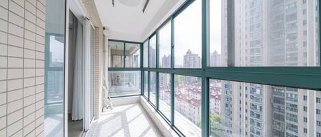 A corridor with large windows, a tiled floor, and a view of high-rise buildings.