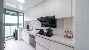 A modern kitchen with white cabinets, a built-in stove, a sink, and a window. - Tyms 3BR 2BA Family Serviced Apt (Shanghai)