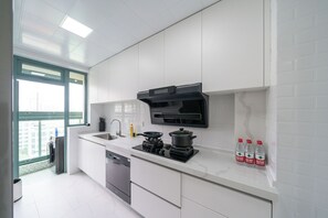 A modern kitchen with white cabinets, a built-in stove, a sink, and a window. - Tyms 3BR 2BA Family Serviced Apt (Shanghai)