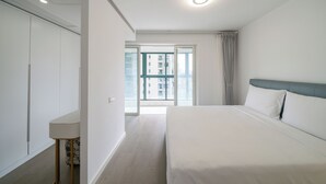 A hotel room with a bed, a desk, a wardrobe, and a view of the outside. - Tyms 3BR 2BA Family Serviced Apt (Shanghai)