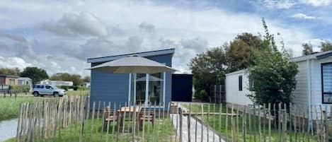 A mobile home with a covered patio, fenced yard, and a small deck.