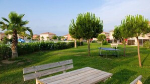 A grassy outdoor area with a wooden bench, a table, and a small table tennis table. - Chalet with On-Site Fitness Room (Fabrègues)