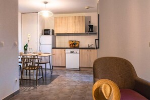 A compact kitchen with a dining area, a microwave, a dishwasher, and a chair.