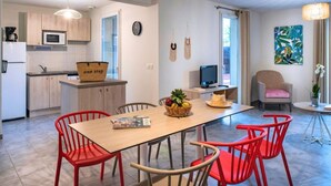 A modern kitchen with a microwave, a basket labeled 'one stop,' and a dining area with a wooden table and red chairs. - Chalet with On-Site Fitness Room (Fabrègues)