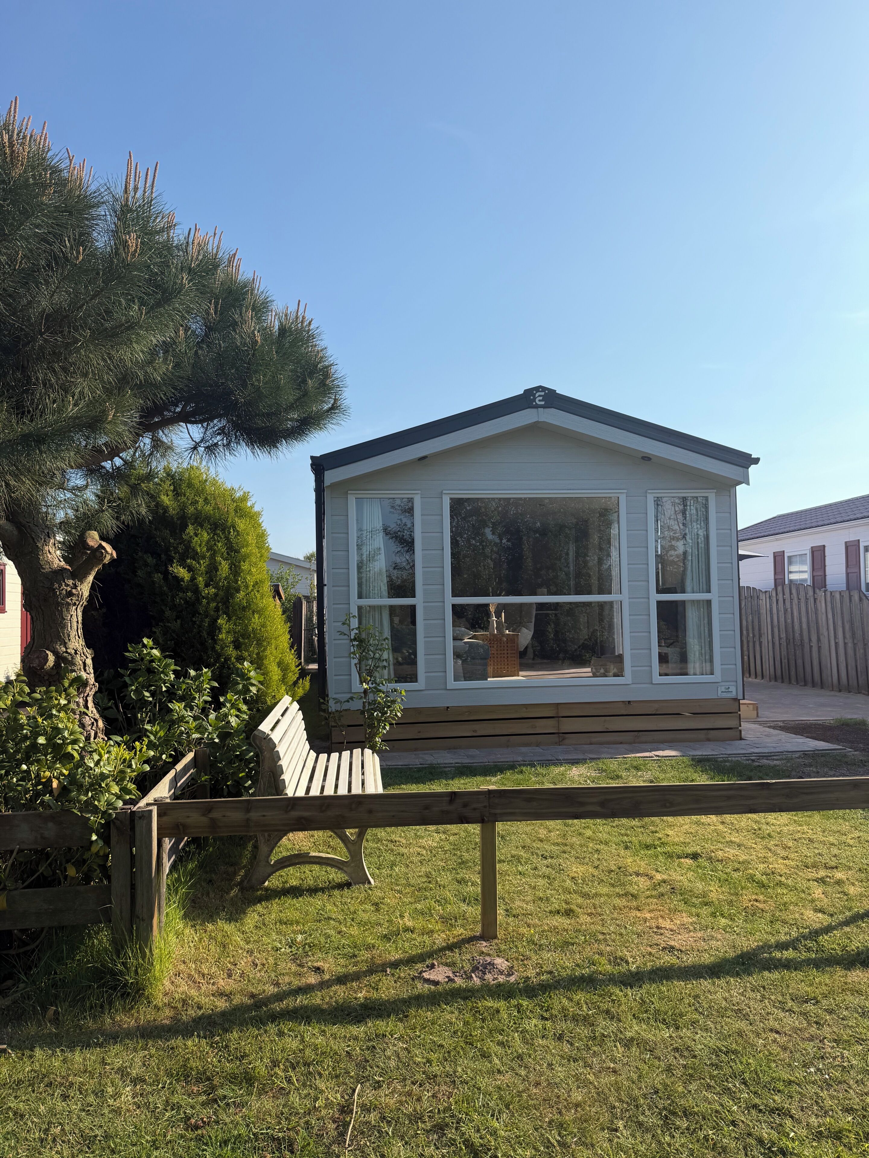 Ein kleines, eingeschossiges Haus mit Satteldach, großen Fenstern und einer Veranda.