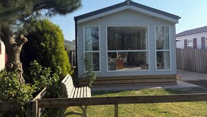 A small, single-story house with a gabled roof, large windows, and a front porch. - Chalet 193 (for 4 persons) (Petten)