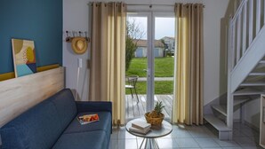 A room with a blue sofa, a small table with a basket, a door leading to a patio, and a staircase. - French Villa with Shared Pool (Fabrègues)