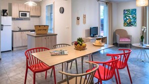 Et moderne køkken med mikrobølgeovn, en kurv med teksten 'one stop' og et spiseområde med et træbord og røde stole.