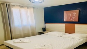 Et hotelværelse med en seng, et natbord, et billedværk på væggen og en loftlampe.
