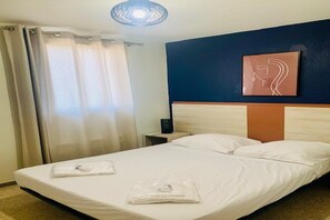 Ein Hotelzimmer mit Bett, Nachttisch, Wandbild und Deckenleuchte.