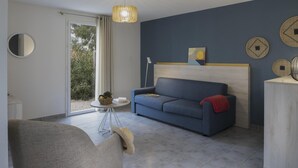 En moderne stue med sofa, stol, et lille bord med en kurv og en lampe.