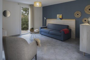 Ein modernes Wohnzimmer mit einer Couch, einem Sessel, einem kleinen Tisch mit einem Korb und einer Lampe.