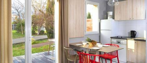 Una cocina moderna con comedor, ventanas amplias y vistas a un jardín.