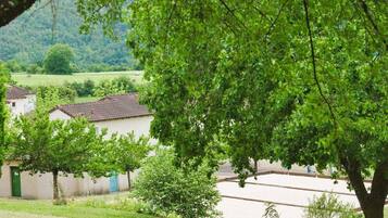 Ein ländliches Dorf mit traditioneller Bebauung, einer von Bäumen gesäumten Straße und Blick auf die Landschaft.