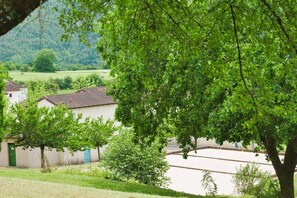 Un pueblo rural con edificios tradicionales, una calle bordeada de árboles y vistas al campo.