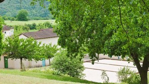 Ein ländliches Dorf mit traditioneller Bebauung, einer von Bäumen gesäumten Straße und Blick auf die Landschaft.