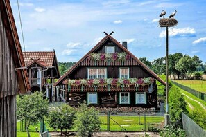 Een traditioneel houten huis met een schuin dak, een balkon vol bloemen en een nest met storks.