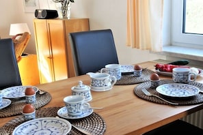 A dining table set with blue and white patterned tableware, a radio, and a wicker basket. - Holiday home in Rerik with swimming pool (Rerik)