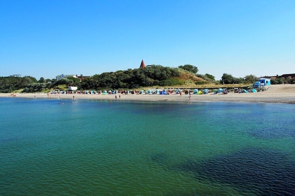 A beach with tents and a hill with a church. - Holiday home in Rerik with swimming pool (Rerik)
