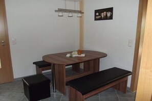 Ein kleiner Essbereich mit einem Holztisch, zwei schwarzen Sitzbänken und einer Wandleuchte.